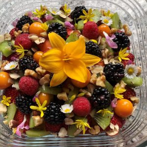Müsli mit frisch geflocktem Hafer, Apfel, Kiwi, Himbeeren, Brombeeren, Physalis, Nüssen, Blüten aus dem Garten